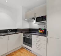 PRENÁJOM - reprezentatívny 2i byt v RIVER PARKU, ideálny aj na firmu - Kuchyňa v 2-izbovom byte s bielymi skrinkami a podlahou s dreveným dekorom.
