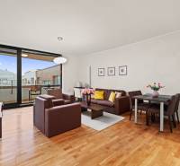 PRENÁJOM - reprezentatívny 2i byt v RIVER PARKU, ideálny aj na firmu - Obývacia izba 2-izbového bytu s posedením, jedálenským stolom a podlahou s dreveným dekorom.