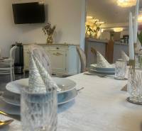 Ponúkame na prenájom zariadený podnikateľský priestor - kaviareň&bar. - Prestreté stoly v gastro priestore s televízorom, zlatými dekoráciami a elegantným stolovaním.