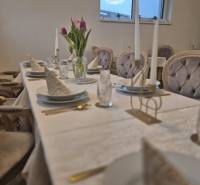 Ponúkame na prenájom zariadený podnikateľský priestor - kaviareň&bar. - Stôl s bielym obrusom, taniere, poháre, kvetiny a prikrývky stoličiek v gastro priestoroch.