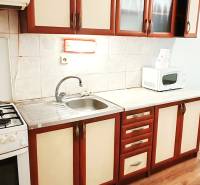 3 izbový byt pri električkovej trati s výhľadom na Draždiak - Kuchyňa v 3-izbovom byte s podlahou s dreveným dekorom a kuchynskou linkou.