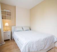 Pozrite si PRÍJEMNÝ 2i byt so ZARIADENÍM, LODŽIOU a KLIMATIZÁCIOU - Spálňa so svetlou stenou a posteľou, vedľa okna je nočný stolík s lampou.