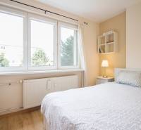 Pozrite si PRÍJEMNÝ 2i byt so ZARIADENÍM, LODŽIOU a KLIMATIZÁCIOU - Svetlá spálňa s posteľou, bielym nábytkom a podlahou s dreveným dekorom v 2-izbovom byte.