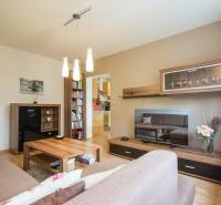 Pozrite si PRÍJEMNÝ 2i byt so ZARIADENÍM, LODŽIOU a KLIMATIZÁCIOU - Obývačka s podlahou s dreveným dekorom, pohovkou a policami v 2-izbovom byte.