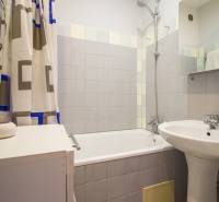 Pozrite si PRÍJEMNÝ 2i byt so ZARIADENÍM, LODŽIOU a KLIMATIZÁCIOU - Kúpeľňa s vaňou, závesom, umývadlom a bielymi obkladačkami v 2-izbovom byte.