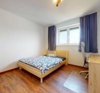 | Exkluzívny 4-izbový byt s obrovskou terasou | Stupava - Spálňa v 4-izbovom byte s dreveným dekorom, jednoduchý nábytok a pracovný stôl.