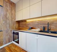 | Exkluzívny 4-izbový byt s obrovskou terasou | Stupava - Kuchyňa v 4-izbovom byte so skrinkami a podlahou s dreveným dekorom.