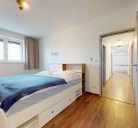 | Exkluzívny 4-izbový byt s obrovskou terasou | Stupava - Spálňa s posteľou a podlahou s dreveným dekorom v 4-izbovom byte.