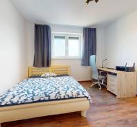 | Exkluzívny 4-izbový byt s obrovskou terasou | Stupava - Spálňa v 4-izbovom byte s posteľou, pracovným stolom a podlahou s dreveným dekorom.