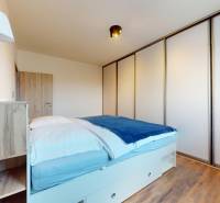 | Exkluzívny 4-izbový byt s obrovskou terasou | Stupava - Spálňa v 4-izbovom byte s veľkou skriňou a podlahou s dreveným dekorom.