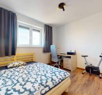 | Exkluzívny 4-izbový byt s obrovskou terasou | Stupava - Spálňa v 4-izbovom byte s posteľou, pracovným stolom a podlahou s dreveným dekorom.