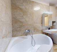 | Exkluzívny 4-izbový byt s obrovskou terasou | Stupava - Kúpeľňa s vaňou a umývadlom v 4-izbovom byte, svetlé mramorové obklady.