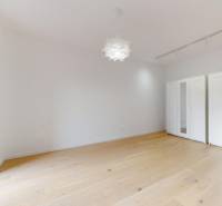 | Prémiové bývanie v ZWIRNe I Pekný 2i byt I  - Priestranná izba s bielou skriňou a podlahou s dreveným dekorom v 2-izbovom byte.