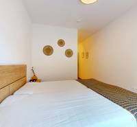 METROPOLIS I Nový Luxusný 2i byt s predzáhradkou I - Spálňa v 2-izbovom byte s posteľou a dekoráciami na stene.