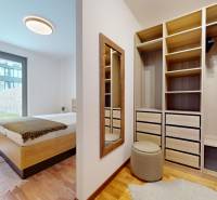 METROPOLIS I Nový Luxusný 2i byt s predzáhradkou I - Spálňa s posteľou, zrkadlom, skriňou a podlahou s dreveným dekorom v 2-izbovom byte.