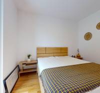 METROPOLIS I Nový Luxusný 2i byt s predzáhradkou I - Spálňa v 2-izbovom byte s posteľou, nočnými stolíkmi a dekoráciami na stene.