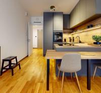 METROPOLIS I Nový Luxusný 2i byt s predzáhradkou I - Kuchyňa v 2-izbovom byte s podlahou s dreveným dekorom, modernými skrinkami a jedálenským stolom.