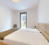 METROPOLIS I Nový Luxusný 2i byt s predzáhradkou I - Spálňa v 2-izbovom byte s manželskou posteľou a podlahou s dreveným dekorom.