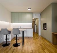 REZERVOVANÉ I METROPOLIS I Luxusný 1i byt I Staré Mesto - Kuchyňa v 1-izbovom byte so svetlou linkou a podlahou s dreveným dekorom.