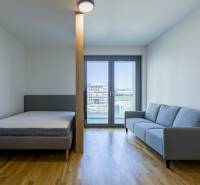 REZERVOVANÉ I METROPOLIS I Luxusný 1i byt I Staré Mesto - 1-izbový byt s posteľou, pohovkou a balkónovými dverami na podlahe s dreveným dekorom.