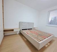 Prenájom: Lukratívny 2-izbový byt v Poprade na Novom nábreží - Spálňa v 2-izbovom byte s podlahou s dreveným dekorom, veľké okno, posteľ a úložný priestor.