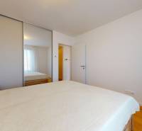 | Prémiové bývanie v ZWIRNe I Pekný zariadený 2i byt I  - Spálňa s posteľou, zrkadlovou skriňou a podlahou s dreveným dekorom v 2-izbovom byte.