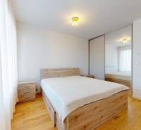 | Prémiové bývanie v ZWIRNe I Pekný zariadený 2i byt I  - Spálňa v 2-izbovom byte s posteľou, zrkadlovou skriňou a podlahou s dreveným dekorom.