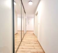 Pekný a moderný 3-izbový byt I Arboria Trnava - Chodba v 3-izbovom byte s podlahou s dreveným dekorom a zrkadlovou skriňou.