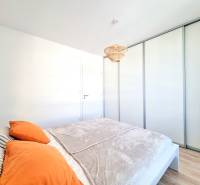 Pekný a moderný 3-izbový byt I Arboria Trnava - Spálňa v 3-izbovom byte s posuvnými skriňami a podlahou s dreveným dekorom.