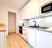 Pekný a moderný 3-izbový byt I Arboria Trnava - Kuchyňa s bielymi skrinkami a podlahou s dreveným dekorom v 3-izbovom byte.