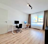 Pekný a moderný 3-izbový byt I Arboria Trnava - Pracovňa v 3-izbovom byte s dvomi stolmi, podlaha s dreveným dekorom, veľké okno.