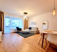 Posledný investičný krásny 2-izbový byt | 62 m² | RÍNOK RAČA - Obývacia izba v 2-izbovom byte so sedačkou, jedálenským stolom a podlahou s dreveným dekorom.