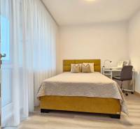 Moderný unikát - 1,5- izb. byt s 2 loggiami na prenájom (Nad jazerom) - Spálňa v 1-izbovom byte s posteľou, písacím stolom a podlahou s dreveným dekorom.