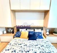 MODERNE A PRAKTICKY ZARIADENÝ 3 IZB. BYT V NOVOSTAVBE NA BOROCH. - Spálňa v 3-izbovom byte s podlahou s dreveným dekorom a kvetinovým obliečaním.