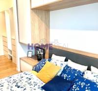 MODERNE A PRAKTICKY ZARIADENÝ 3 IZB. BYT V NOVOSTAVBE NA BOROCH. - Spálňa v 3-izbovom byte s posteľou, farebnými vankúšmi a úložnými priestormi.