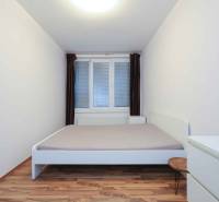 Predaj útulný 2 izbový byt, novostavba, super lokalita Jégeho ulica. - Spálňa v 2-izbovom byte s bielym nábytkom a podlahou s dreveným dekorom.