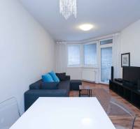 Predaj útulný 2 izbový byt, novostavba, super lokalita Jégeho ulica. - Obývačka 2-izbového bytu s gaučom, televízorom a podlahou s dreveným dekorom.