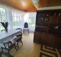 Ponúkame na predaj záhradný domček - Jasová - Jedáleň v rodinnom dome s dreveným dekorom, nábytkom a veľkými oknami.