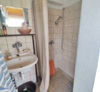 Ponúkame na predaj záhradný domček - Jasová - Kúpeľňa v Rodinnom dome s jednoduchým sprchovým kútom a závesom, svetlé obkladačky.