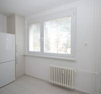 3-izb.byt v Dúbravke (Gallayova ul.) po rekonštrukcii s loggiou - Izba v 3-izbovom byte s bielymi stenami, radiátorom a chladničkou.