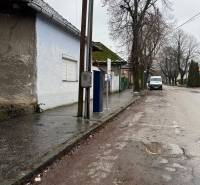 Predáme rodinný dom- Šurany, širšie centrum.  - Rodinný dom na Komenského ulici v Šuranoch, pri ceste s elektrickým stĺpom a stromami.