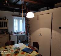 ČREMOŠNÉ-chalupa na pozemku 700m2   - Kuchyňa v rodinnom dome s dreveným stropom, stolom a jednoduchým nábytkom.