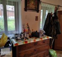 ČREMOŠNÉ-chalupa na pozemku 700m2   - Drevená komoda v rodinnom dome obklopená predmetmi, obrazy, zavesená bunda.