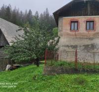 ČREMOŠNÉ-chalupa na pozemku 700m2   - Rustikálny rodinný dom s trávnikom a oplotením, obklopený stromami a lesom.