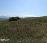 VALČA pozemok s výmerou 5800 m2,  okr. Martin  - Krajina s trávou a kríkmi, rekreačné pozemky s horským pozadím a jasná obloha.