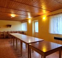 Predaj Domu v obci Lovča - Jedáleň v rodinnom dome s drevenými stropmi, dlhými stolmi a stoličkami, svetlá výzdoba.