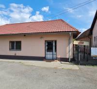 Predaj Domu v obci Lovča - Rodinný dom v Lovči so šikmou červenou strechou a reklamnou tabuľou na predaj.