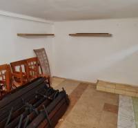 Predaj Domu (obchodného priestoru) v obci Lovča - Prázdna miestnosť s policami, stoličkami a dvoma malými oknami v rodinnom dome.