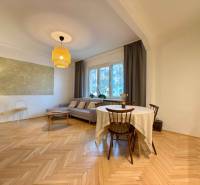 2-izbový byt 45m2 | Sklenárová - Ružinov - Obývacia izba v 2-izbovom byte s hnedou sedačkou a podlahou s dreveným dekorom.