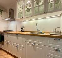 2-izbový byt 45m2 | Sklenárová - Ružinov - Svetlá kuchyňa v 2-izbovom byte s podlahou s dreveným dekorom a bielymi skrinkami.